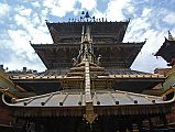 Kathmandu Patan Golden Temple 07 Main Temple With Swayambhu Chaitya In Front The large rectangular Golden Temple in Patan has three roofs and a copper-gilded fa�ade. The long metal strips coming down from the roof are supposed to provide a slide for the gods when they descend to answer prayers. In the foreground is the roof of the Swayambhu Chaitya.